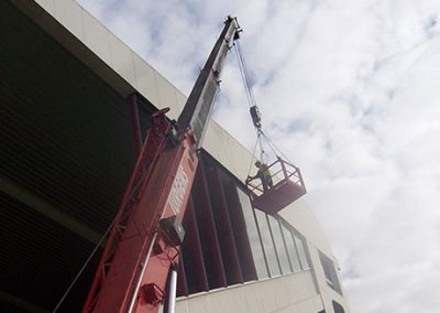 Crane lifting a work platform up the side of the Arena Manawatu grandstand