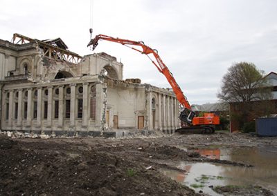 High reach excavator working along the colonnaded side wall of the Cathedral of the Blessed Sacrament