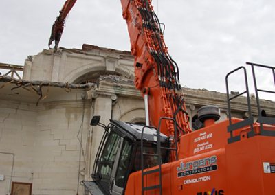 Close view of a Jurgens Contractors high reach excavator lifting stonework from the cathedral wall