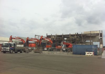 Row of Jurgens excavators and a truck working on the partly deconstructed Fonterra Longburn plant
