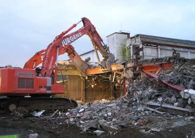 Jurgens excavator pulling down the timber and steel structure of the Makarewa freezing works at dusk