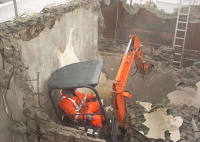 Mini excavator breaking out a concrete wall from inside the structure at Makarewa