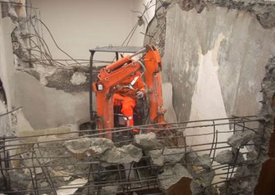 Mini excavator working on a reinforced concrete floor inside the Makarewa building