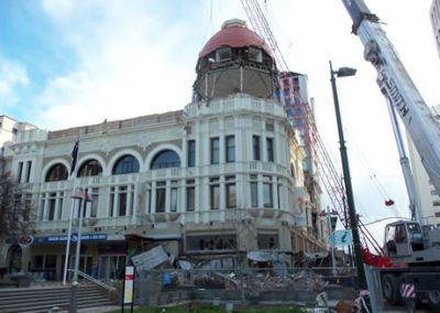 The Regent Buildings with its red-domed tower being deconstructed, a mobile crane alongside