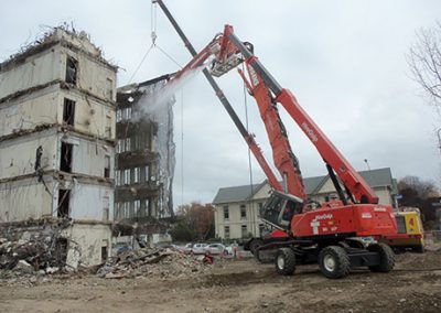 Wheeled high reach excavator and crane working together on a damaged multi-storey building