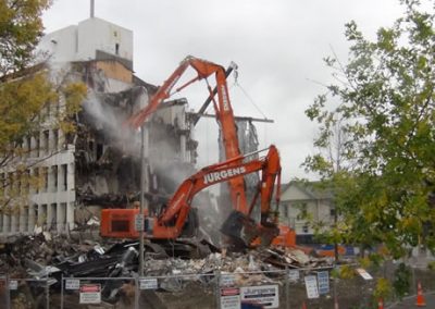 Jurgens excavator demolishing Scales House with dust suppression spray in use